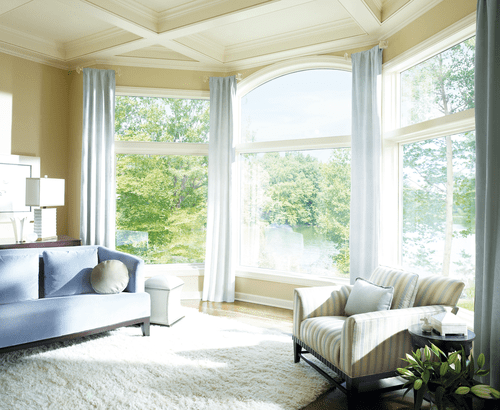 A living room with large windows and white furniture.