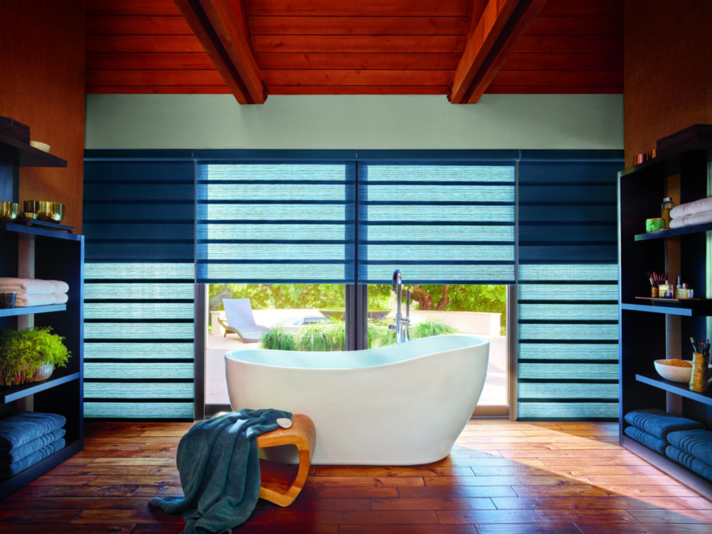 A bathroom with a tub and window blinds.