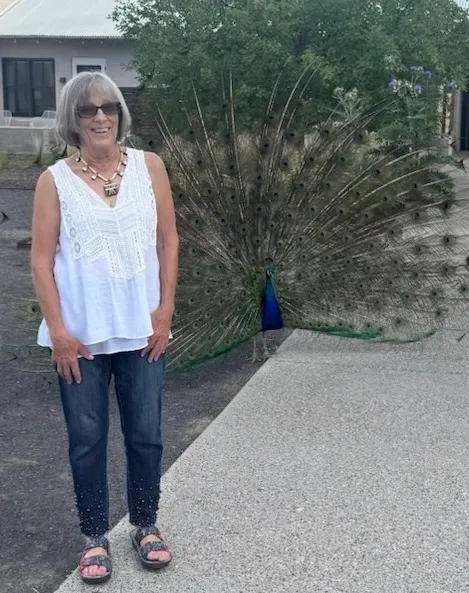 Woman smiling beside peacock with fanned tail